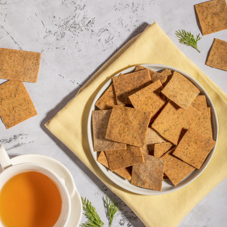 A bowl of dill crackers accompanied by a cup of tea