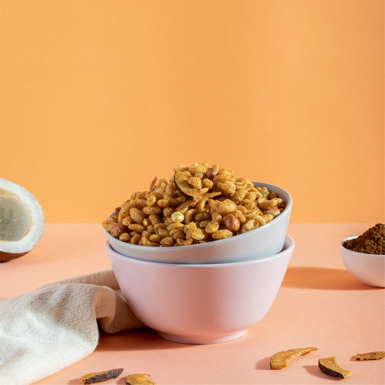 Muri Bhel in a bowl with a coconut and some dried coconut slices around the bowl