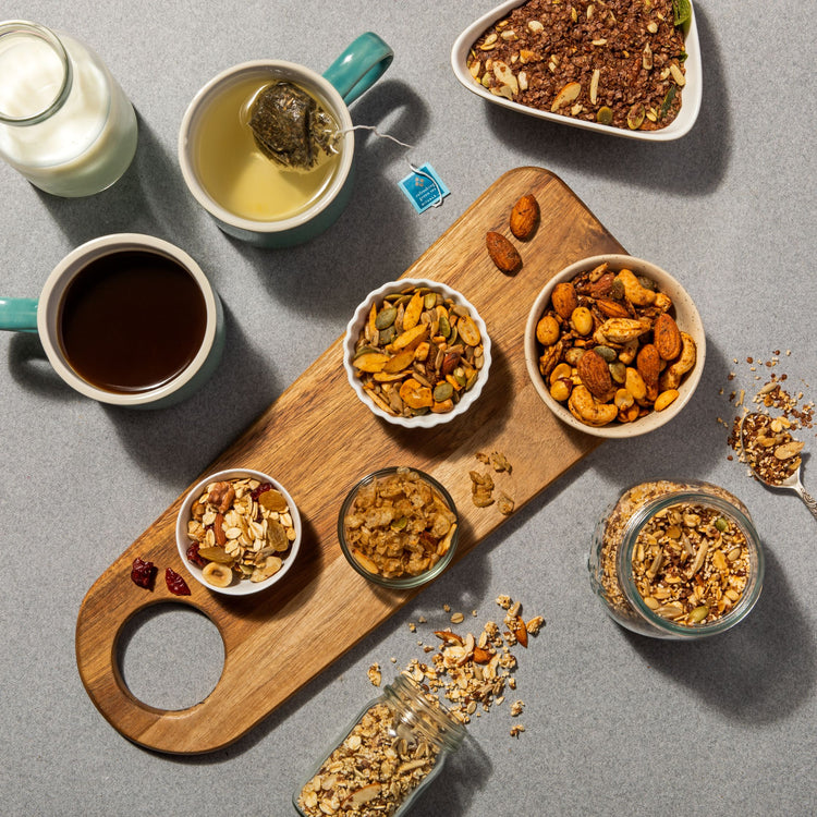 Multiple mixed snacks placed on a wooden tray with milk and coffee next to it.